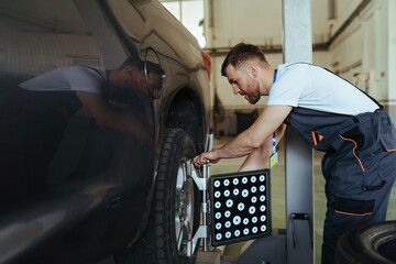 Car mechanic installing sensor  adjustment and automobile wheel