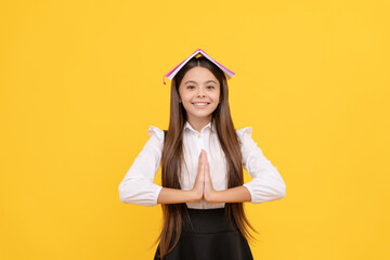 happy teen girl in school uniform with book on head meditating with hand gesture, keep calm