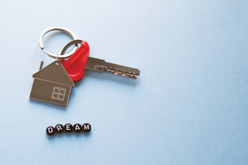 keychain in the form of a house with a key to a new apartment, an inscription from black dream cubes on a blue background, space for text