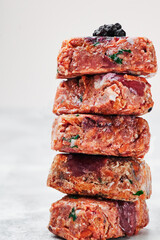 Composition with raw square cutlets on light background. Natural food for dogs. BARF dog diet. Close up