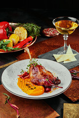 Duck leg with pumpkin puree, berry sauce and soy sprouts on a white plate on a copper background, served with white wine.