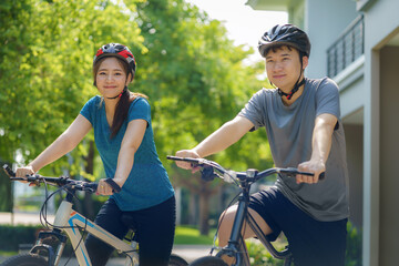 Asian couple wearing a helmet while preparing for a bike ride around her neighborhood for daily...