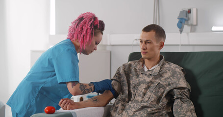 Young man soldier giving blood in hemotransfusion center
