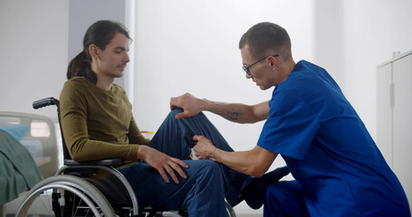 Fototapeta na wymiar Rehabilitation doctor massaging leg of patient in wheelchair