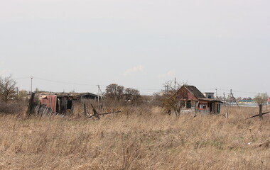 Abandoned small country houses in a field among dry grass