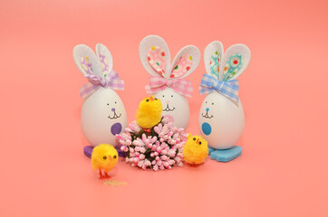 Artificial eggs rabbits, on a pink background with a yellow chicken, art staging