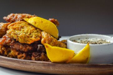 Delicious onion bhaji fritters served on wooden plate with white dip