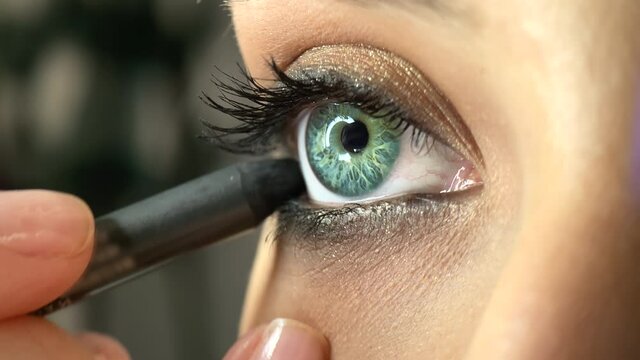 MUA applies black eyeliner on the lower eyelid. Close-up of female model while having her eye make-up done. High quality 4k footage