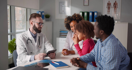 Young african parents with little daughter visiting family doctor in clinic