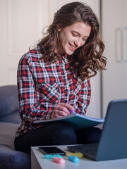 one young woman, smiling and happy, reading or writing in book.