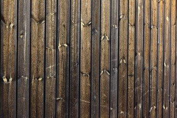 Texture of barn wall made from homemade rough sawn timber. Knotty boards treated with varnish and pine tar.