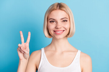 Photo of happy cheerful nice young woman hold hand show v-sign smile isolated pastel blue color background