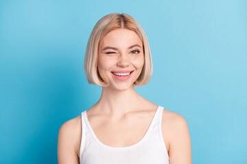 Fototapeta premium Close-up portrait of charming cheerful blond girl winking flirting isolated over vibrant blue color background