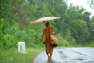 buddhist monk walking on the road under the rain