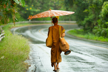 buddhist monk walking on the road under the rain