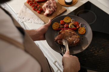 Man with tasty meat and vegetables cooked on frying pan, above view