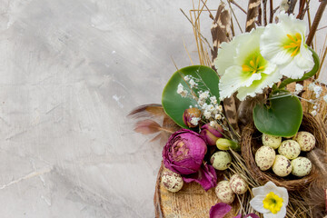 Easter composition with eggs, feathers and flowers on grey background