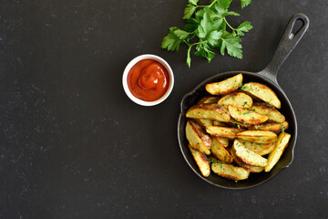 Fried potato wedges with spices in frying pan