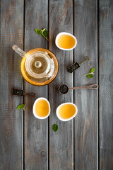 Fototapeta premium Teapot and cups with green tea, top view. Flat lay of tea ceremony concept.