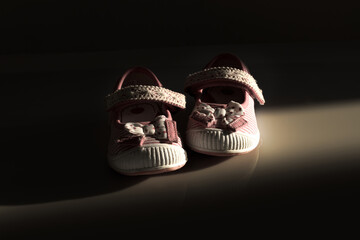 Conceptual image of violence to kids represented with a pair of baby shoes on a dark background