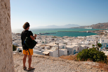 Young tourist observes the panorama of the village of Chora on the island of Mykonos in Greece. In...