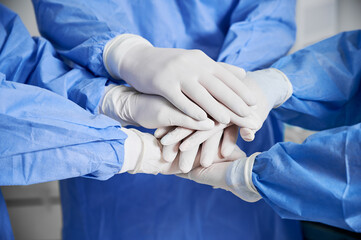 Close up of medical workers joining their hands together as symbol of unity. Group of doctors with...