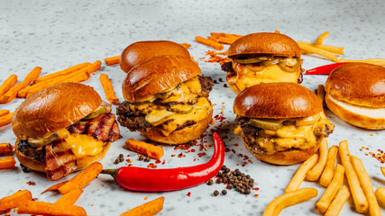 A closeup shot of tasty smash burgers, French fries, and red spicy peppers on the white background - obrazy, fototapety, plakaty