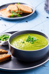 Fresh homemade peas cream soup with mint and toasted bread.
