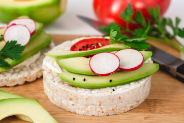 Rice cake sandwich with cheese cream, avocado, tomato, radish and spices. A healthy dietary snack