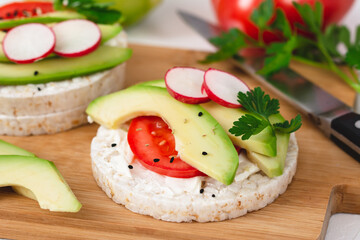 Rice cake sandwich with cheese cream, avocado, tomato, radish and spices. A healthy dietary snack