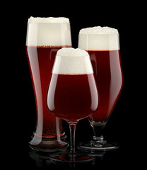 Set of fresh draft beer glasses with bubble froth isolated on black background.