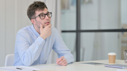 Naklejka premium Young Man Sitting in Office Thinking 