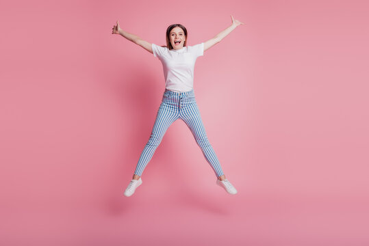 Portrait Of Sportive Childish Funky Girl Jumping In The Air Wear Casual Denim Outfit On Pink Wall