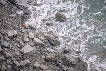 Plage de rochers en Bretagne, vu de haut, avec l'eau qui avance vers la plage