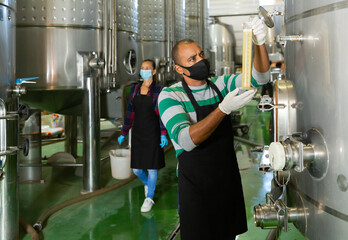 Winemaker in protective masks analyze the white wine in a beaker