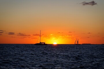 Naklejka na ściany i meble Sunset and sailboat silhouettes on the horizon viewed from Mallory Square, Key West, USA