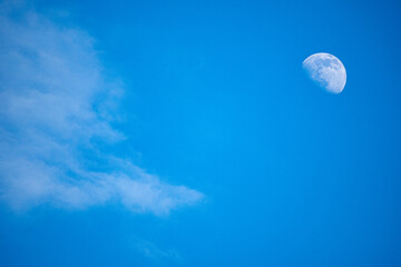 Beautiful Moon on a blue sky with white cloud coming to cover it