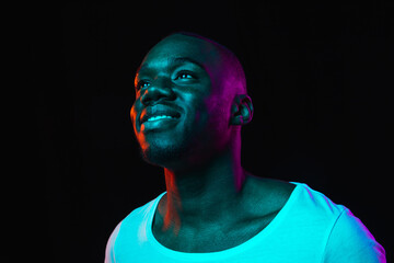 Young happy African-American man isolated on dark background in neon light