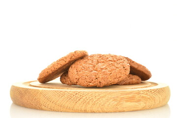 Several fragrant dark brown, oatmeal cookies on a wooden tray, close-up, isolated on white.