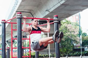 Young, athletic Latino male doing muscular exercise in the open air.