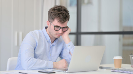 Young Man with Laptop Taking Nap in Office 