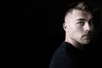 Portrait of handsome man with beard standing next to window with blue eyes.