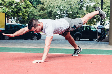 Young, athletic Latino male doing muscular exercise in the open air.