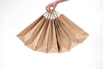 Eco-friendly paper bags for gifts and shopping in a woman's hand on a white background