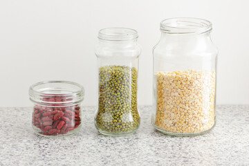Variety of dry legumes: kidney bean, peas, green gram in glass jars uncooked on white kitchen background, zero waste, eco friendly, balanced diet food, healthy clean eating, vegan protein concept