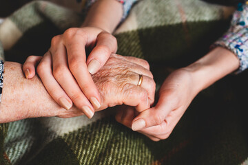 Holding hands of old and young women.