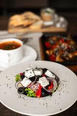 A hearty lunch in a cafe on the table, pate with croutons, bograch, Greek salad and a frying pan with veal. lunch for one person. dishes. kitchen.