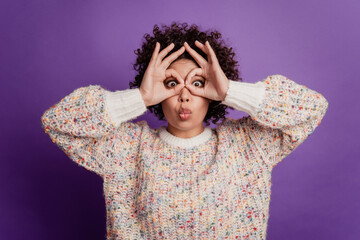 Portrait of young woman showing binoculars with fingers grimacing