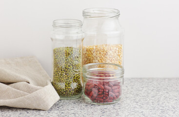 Variety of dry legumes: kidney bean, peas, green gram in glass jars uncooked on white kitchen background, zero waste, eco friendly, balanced diet food, healthy clean eating, vegan protein concept