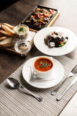 A hearty lunch in a cafe on the table, pate with croutons, bograch, Greek salad and a frying pan with veal. lunch for one person. dishes. kitchen.